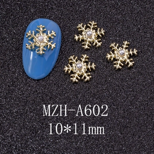 Macro detail of 10x11mm gold snowflake nail charms with faux pearls on blue manicure