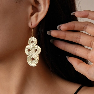 Close-up of golden wrinkled metal geometric hoop earrings on female model with soft lighting