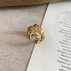 Close-up of a gold laurel leaf open ring on a book page with minimalist aesthetic