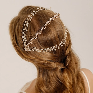 Detail view of golden leaf headband with white pearls on elegant bridal hairstyle
