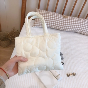 Dettaglio della mini borsa trapuntata bianca con motivo floreale 3D su un letto