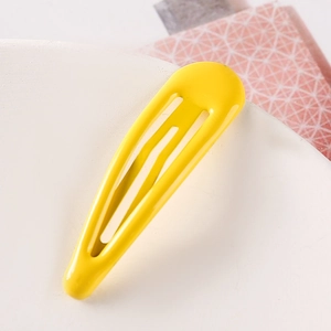 Macro view of bright yellow teardrop metal hair clip with smooth drip lacquer finish