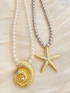 Detail of gold starfish and conch pendants with pearls on champagne silk background