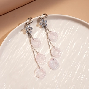 Detailed close-up of tassel earrings with resin shell petals and crystal flower studs