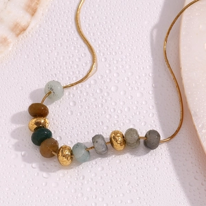 Macro d'un collier chaîne serpent en or 18K avec pierres naturelles et décor de coquillage