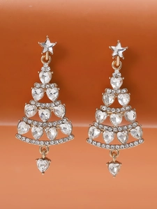 Macro shot of gold Christmas tree earrings with sparkling crystals on warm background
