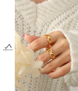 Detail of 18K gold plated figure-eight hollow ring worn on hand with cozy knitwear