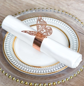 Close-up of laser-cut rose gold butterfly napkin ring on a white napkin