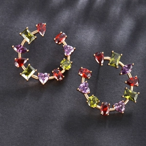 Detailed macro view of gold-plated earrings with colorful zircon gemstones in various shapes