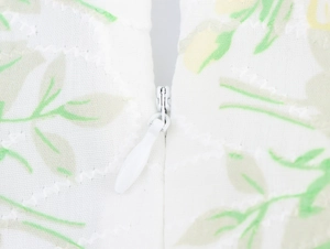 Close-up of invisible zipper detail on white floral embroidered V-neck maxi dress