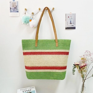 Detail of colorful woven straw tote bag with red and green stripes on a white wall