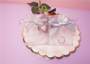 Detail of light purple and silver organza gift bags with satin bows on a decorative tray