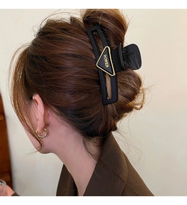 Detail view of a triangle hair claw clip with POWER lettering on a stylish bun hairstyle