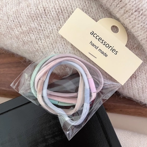 Macro view of pastel-colored elastic hair ties in a pack with a handmade tag label