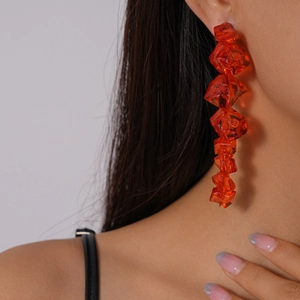 Close-up of long orange acrylic earrings with irregular geometric beads on a model