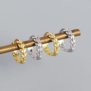 Detailed view of leaf-shaped hoop earrings in polished gold and silver finishes