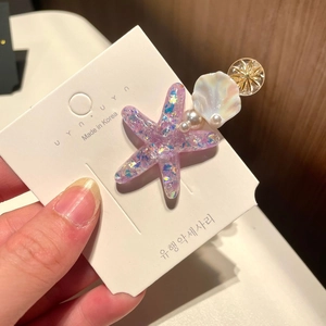 Detailed close-up of starfish hair clip with imitation pearls and pink resin shells