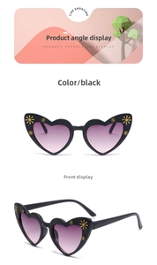 Detail of heart-shaped kids sunglasses with black frames and golden daisy accents