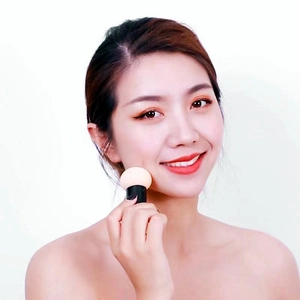Detail of beige mushroom head makeup sponge being applied on face with black handle