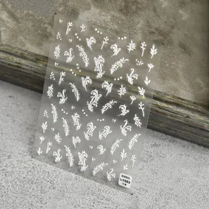 Macro detail of embossed white floral nail art decals with 5D texture on a transparent sheet