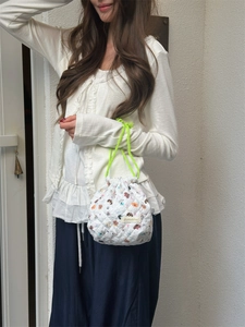 Detail view of a quilted cartoon drawstring bag with lime green cord held by model