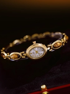 Detailed macro view of gold-tone bracelet watch with oval tiger eye stone inlays