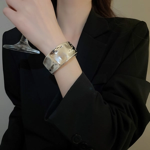 Detail of silver textured wide cuff bracelet with irregular hammered metal finish on model