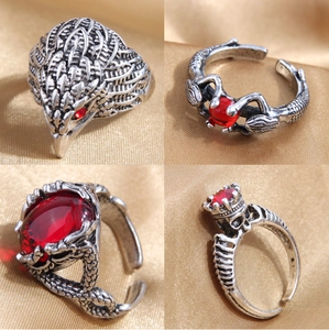 Macro view of four gothic rings with red rubies on golden satin fabric background