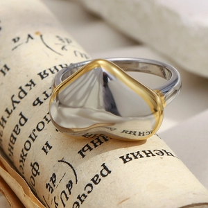Detailed view of two-tone 18K gold and silver heart ring on a vintage scroll paper