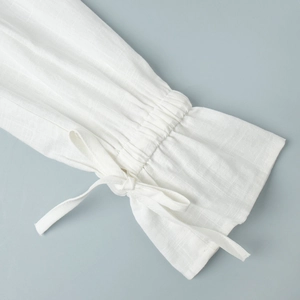 Detail of white cotton shirt sleeve with ruffled elastic cuffs and a delicate ribbon tie