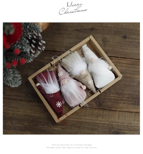 Set of four plush Christmas gnome ornaments in a craft gift box on a wooden background