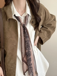 Détail d'un foulard en mousseline à motif cachemire sur une veste en daim marron