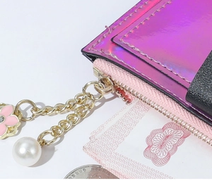 Macro detail of laser holographic card holder with pink enamel flower and pearl chain