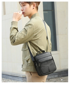 Detail of black cross-body bag featuring lychee grain texture and zipper pockets