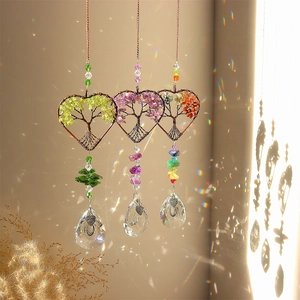 Detailed view of three tree of life heart suncatchers reflecting rainbow light on a wall