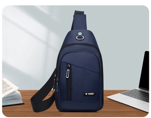 Detail view of water-resistant navy nylon chest bag with multiple zipper pockets on a desk
