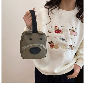 Close-up of military green nylon cartoon dog handbag with 3D bear face and zipper detail