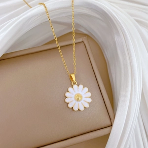 Macro shot of titanium steel daisy pendant with white petals on a luxury gold chain