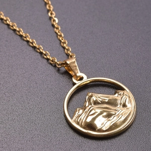 Macro shot of 18K gold plated mountain range pendant with textured relief on chain