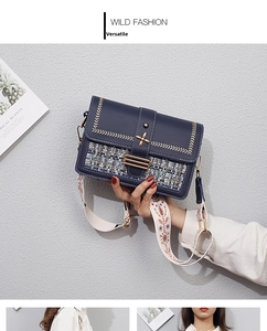 Detail of navy blue PU crossbody bag featuring metallic floral buckle and ethnic woven strap