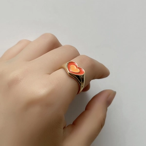 Detail of model wearing gold enamel double heart ring with pink and orange colors