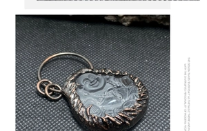Makroaufnahme von Buddha-Anhänger aus Glas mit antikem Bronze-Metallrahmen im Vintage-Stil