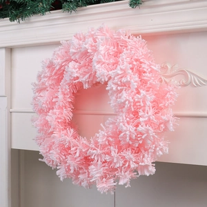 Pink flocked Christmas wreath with snowy texture hanging on a white fireplace