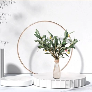 Artificial olive branches with colorful fruits in a glass vase for home decor