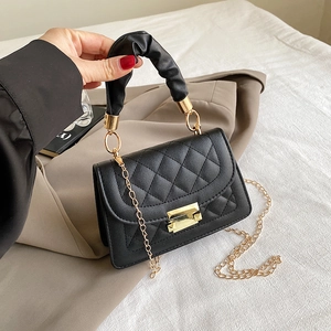 Detalle de bolso acolchado negro con cierre dorado y diseño de asa fruncida