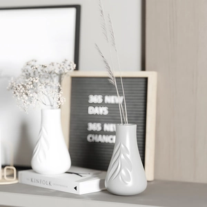 Detail of minimalist leaf embossed ceramic vases in white and grey for home decor
