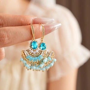 Gros plan de boucles d'oreilles vintage en or avec pierres bleues et détails de perles