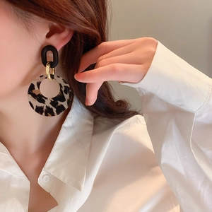 Close-up of leopard print hoop earrings with black matte rings on model's ear