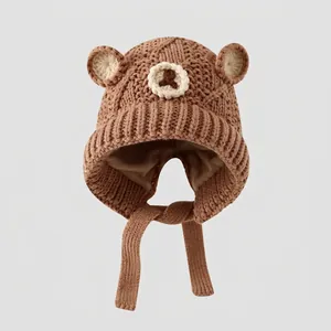 Close-up of brown knitted cotton winter hat with bear ears and chin strap for kids