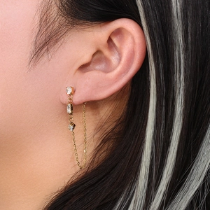 Macro shot of long gold chain earrings with zircon stones worn by a female model